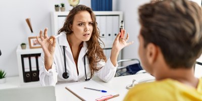 Doktorka drží cigaretu a elektronickou cigaretu