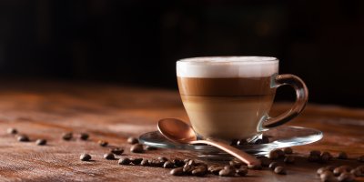 Šálek kávy se lžičkou a kávovými boby