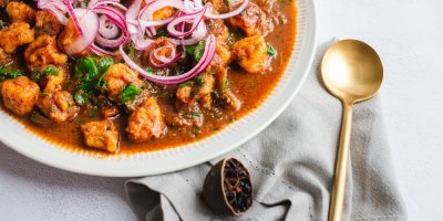 Talíř s pokrmem a vedle černá limeta s vařečkou