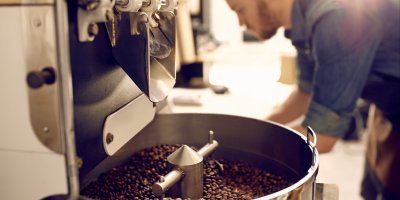 Muž sklánějící se nad pražírnou kávy