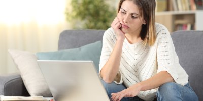 Žena si znuděně prohlíží e-shop na notebooku