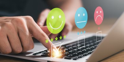 Trojice smajlíků nad rukou tisknoucí klávesu notebooku