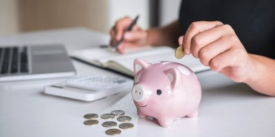 Žena počítá výdaje a dává peníze do prasátka