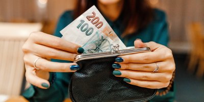 Žena si ukládá bankovky do peněženky