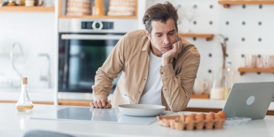 Muž se v kuchyni dívá na pánev a  na vejce