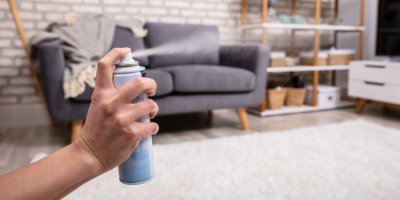 Ruka stříká osvěžovač vzduchu v obyváku