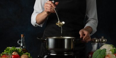 Profesionální kuchař nabírá polévku naběračkou