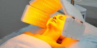 Žena podstupuje péči o pleť obličejovou lampou na klinice