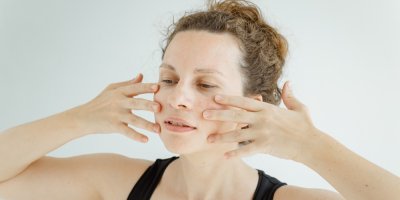 Žena si drží prsty na obličeji