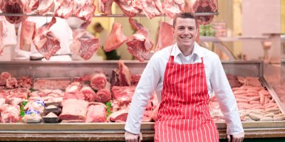 Řezník je opřený o pult s masem