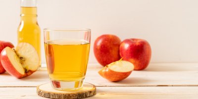 Jablečný ocet ve sklenici a rozkrájená jablka