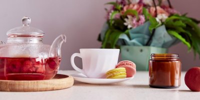 Pečený čaj s malinami v konvičce, šálek s makronkami a dóza