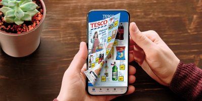 Ruka držící mobil s letákem Tesco