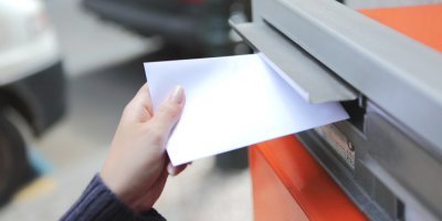 Ruka hází obálku do poštovní schránky