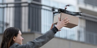 Žena přebírá zásilku od dronu