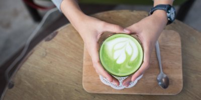 Ruce držící hrnek s čajem matcha