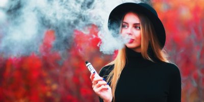 Žena drží vaporizér a vyfukuje kouř