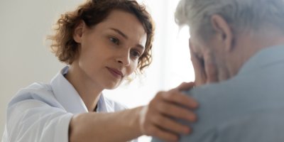 Žena pokládá smutnému muži ruku na rameno