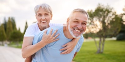 Starší muž nese ženu na zádech a smějí se