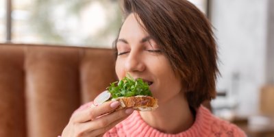 Žena kouše do chleba s rukolou a ředkvičkou