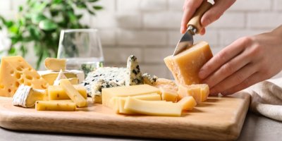 Člověk krájí různé druhy sýrů na prkénku