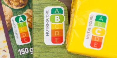 Detailní záběr na obaly tří výrobků, na nichž je Nutri-Score. První má hodnotu A, druhý B a třetí C