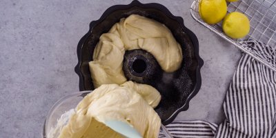 Člověk vlévá těsto z mísy do formy na bábovku