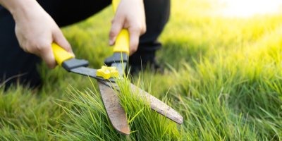 Člověk stříhá nůžkami trávník