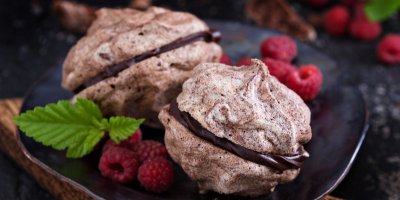 Sněhové čokoládové pusinky na černém talíři s malinami