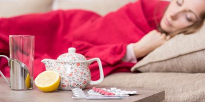 Ležící žena s konvičkou čaje, prášky a citronem