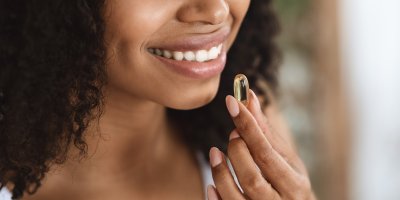 Žena drží jednu vitaminovou kapsli