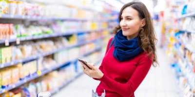 Žena v supermarketu s mobilním telefonem