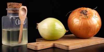 Dvě cibule na prkénku a sirup v lahvičce se lžičkou