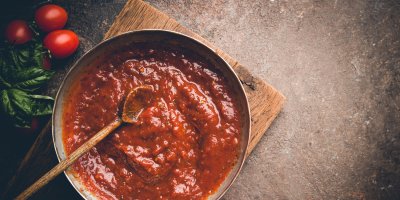 Domácí rajčatová omáčka v hrnci, vařečka, rajčata