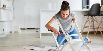 Žena natírá starou židli bílou barvou