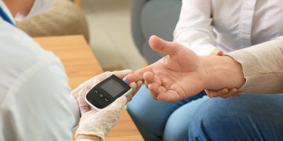 Doktorka měří muži hladinu cukru v krvi