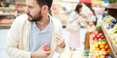 Muž se dívá za sebe a strká si nektarinku pod bundu