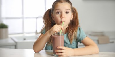 Dívka pije kakao u stolu