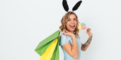 Žena v králičích uších drží vajíčka a nákupní tašky