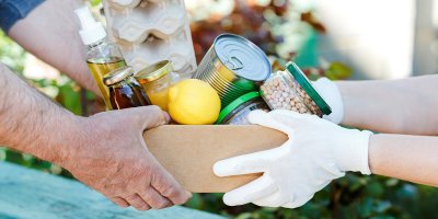 Dva lidé si předávají papírový box s potravinami