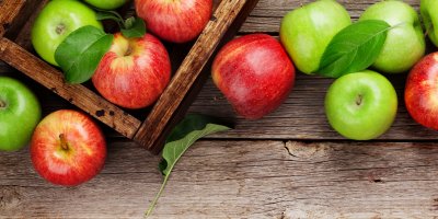 Červená a zelená jablka v bedýnce i kolem ní