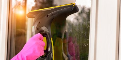 Žena čistí okno vysavačem na okna