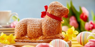 Velikonoční beránek s barevnými vajíčky v popředí