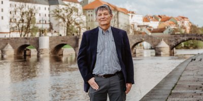 Muž stojí na nábřeží, v pozadí je most