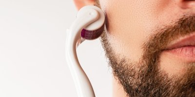 Vousatý muž si přikládá dermaroller na tvář