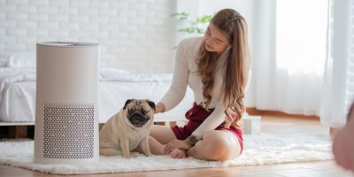 Žena se psem sedí vedle čističky vzduchu