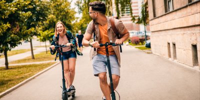 Muž a žena jedou na elektrokoloběžkách