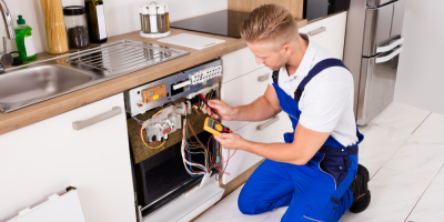 Muž opravuje v kuchyni myčku