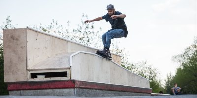 Muž dělá triky na kolečkových bruslích