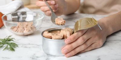 Člověk nabírá vidličkou tuňáka z konzervy